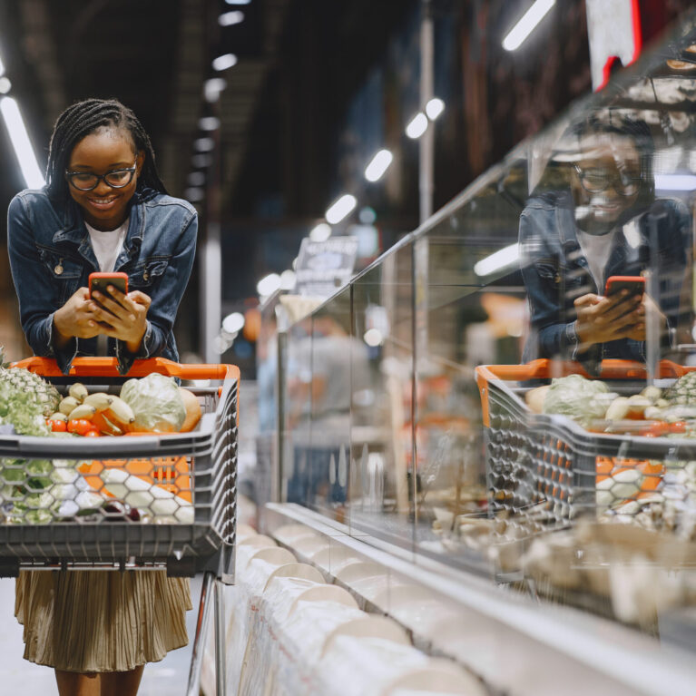 African woman with shopping cart. Girl in a supermarket.